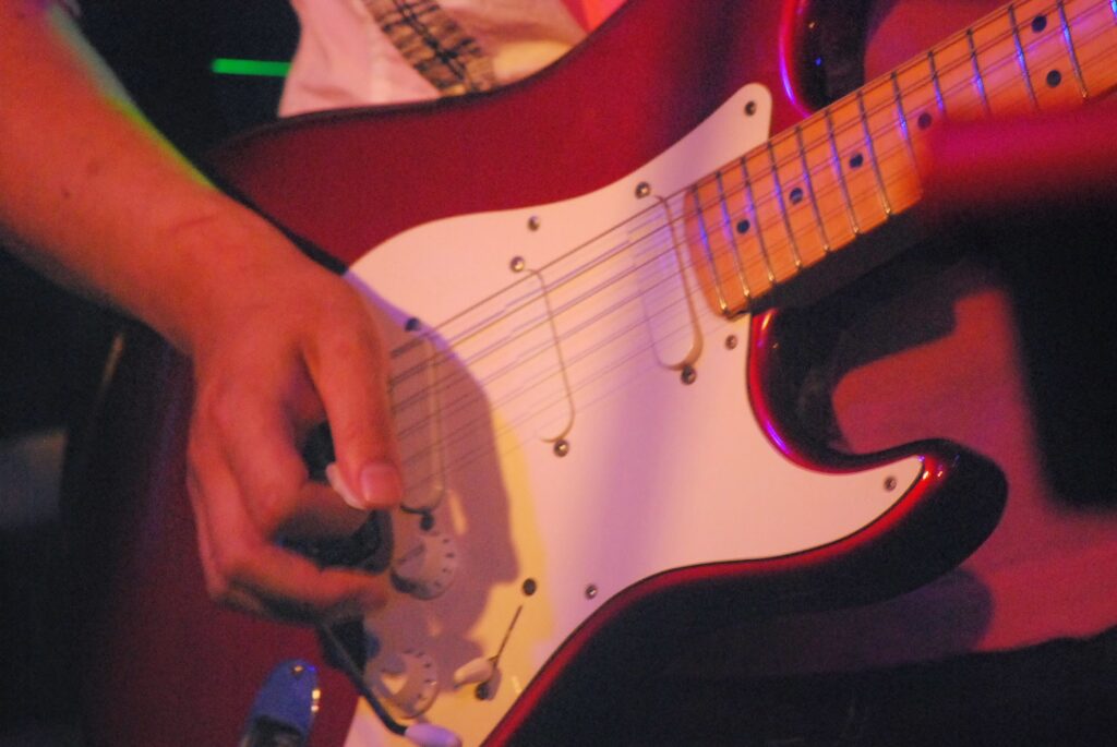Fender Stratocasterのピックアップ周辺を弾く右手のクローズアップ