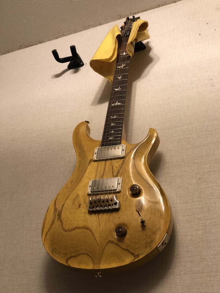 木目を生かしたナチュラル仕上げのPRS Custom 22を壁掛けギターハンガーに掛けた様子